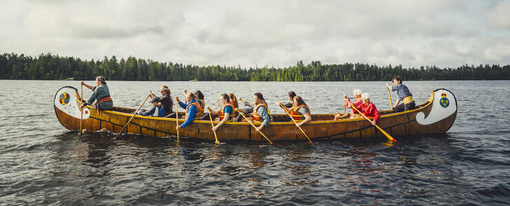 A group of people paddling a voyageur canoe.