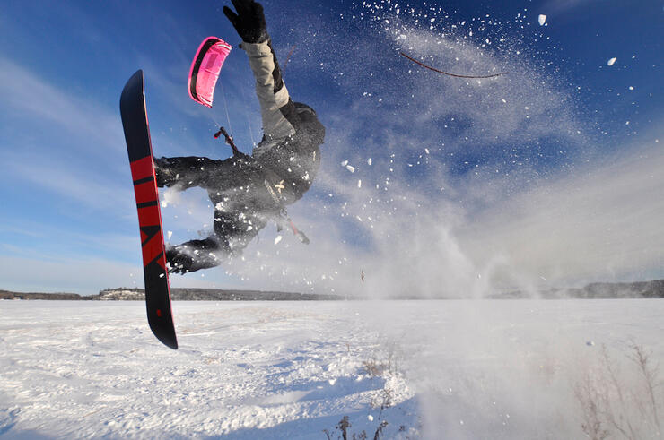 Person catching some air on a snowboard on a frozen lake