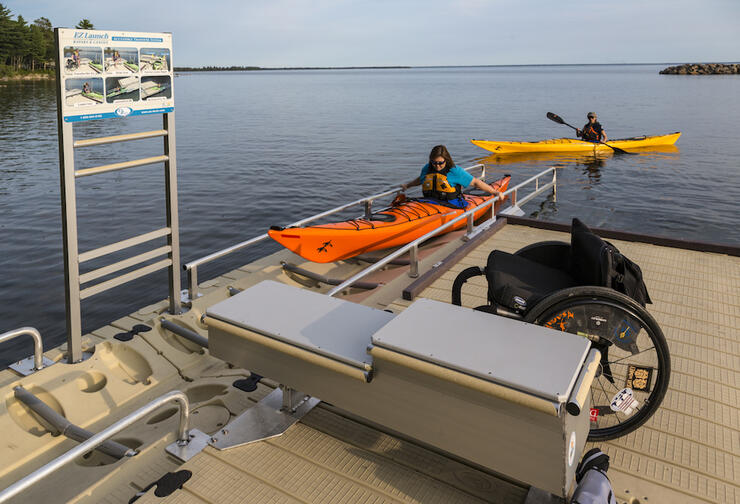 Woman in a kayak coming up on a dock on a accessible ramp