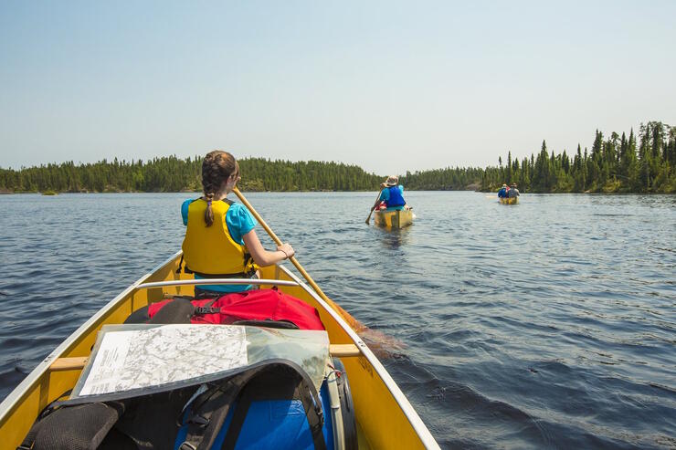 Young girl paddling in the bow of a canoe.