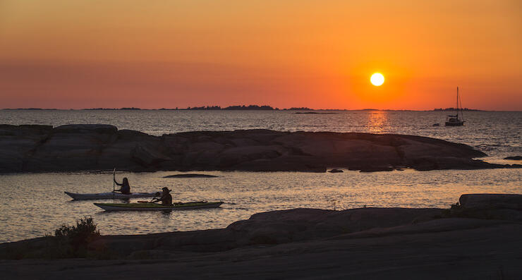 Two kayaks paddling in sheltered bay with beautiful sunset