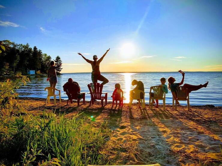 7 people sitting or standing on beach on beautiful sunny day.