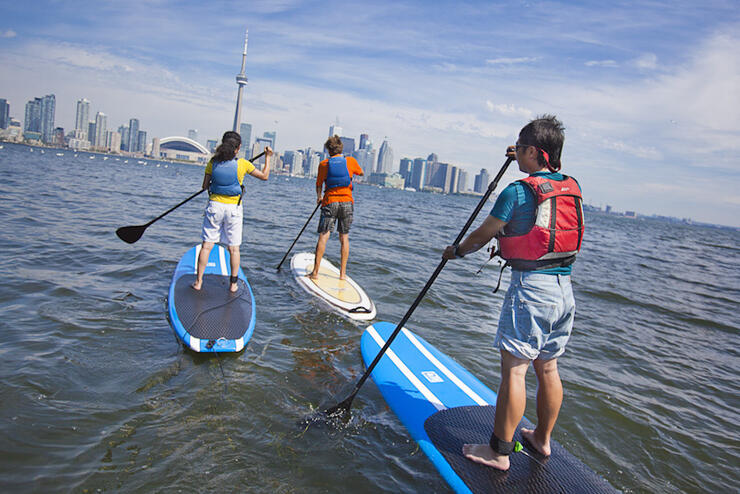 Three standup paddleboarders paddling towards Toronto