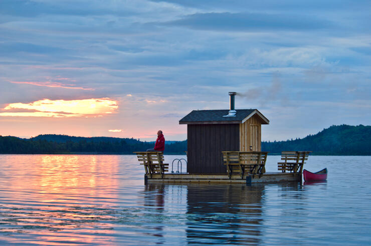 Sauna with deck and canoe floating on a lake at sunset