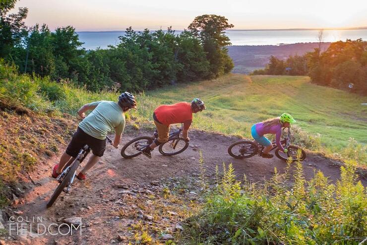 Three people riding mountain bikes on a rocky trail. 