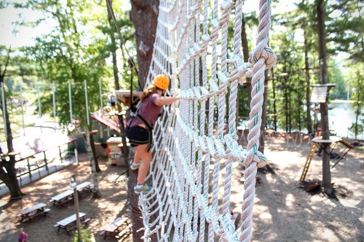 Kids in harness on a net wall.