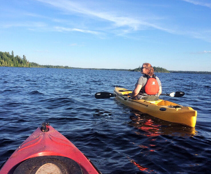 Two kayakers paddling on a beautiful lake.