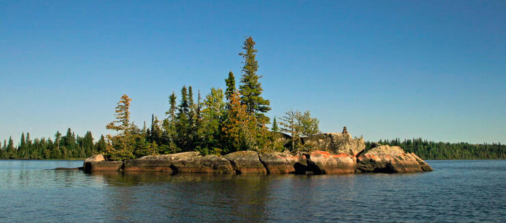 Small rock island with coniferous trees.