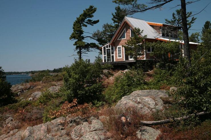 Small cottage perched on smooth rocks with a few pine trees.