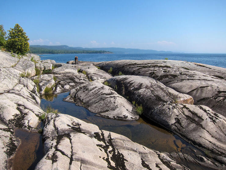 Hiker in distance on flat rocky shoreline on Lake Superior 