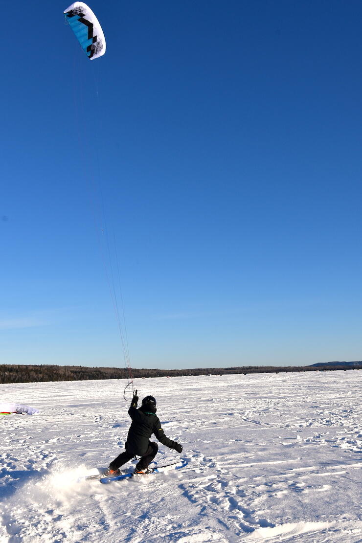 Person on snowboard carving a turn while holding snowkite.
