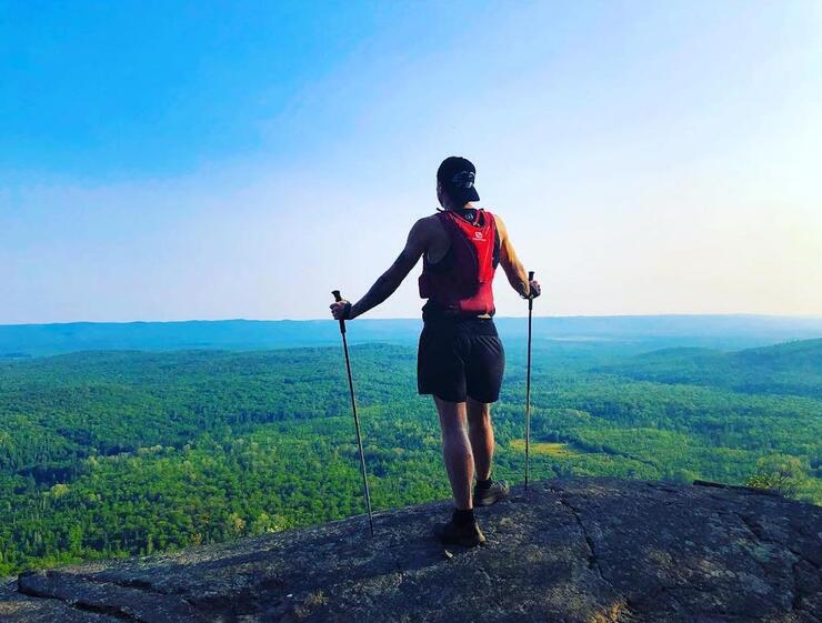 Person standing on a high rock overlooking expanse of forest.