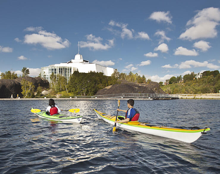 Two kayakers paddling in front of Science North