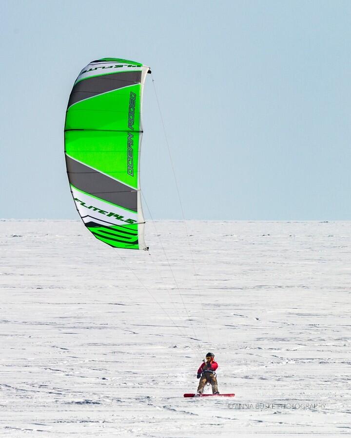 Person snow-kiting on frozen lake.
