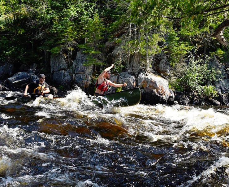 Two people in canoe running rapids