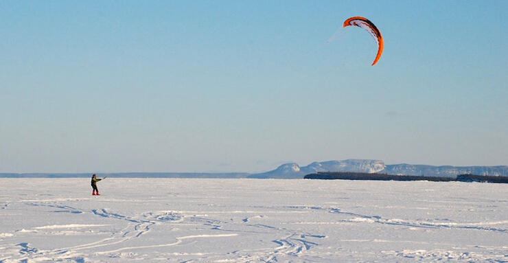 Person snowkiting on a frozen lake.