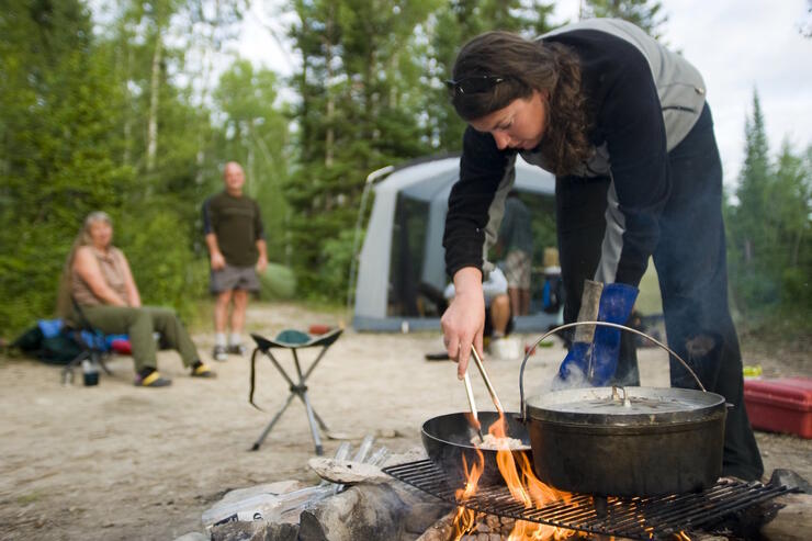 Woman cooking over a campfire.