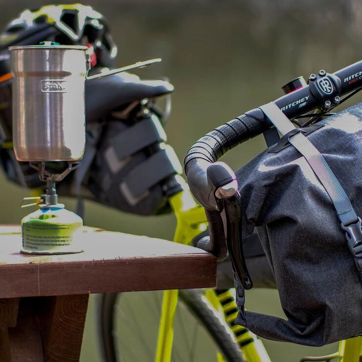 Bicycle leaning against a picnic table with a lantern on it.