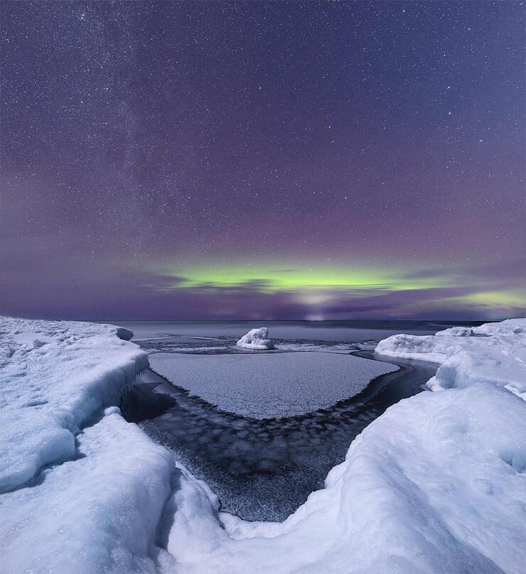 Nightscape of snow-covered land and starry sky.