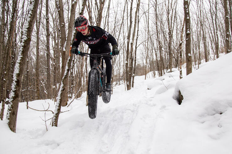 Man on fat tire mountain bike catching some air on a winter trail.