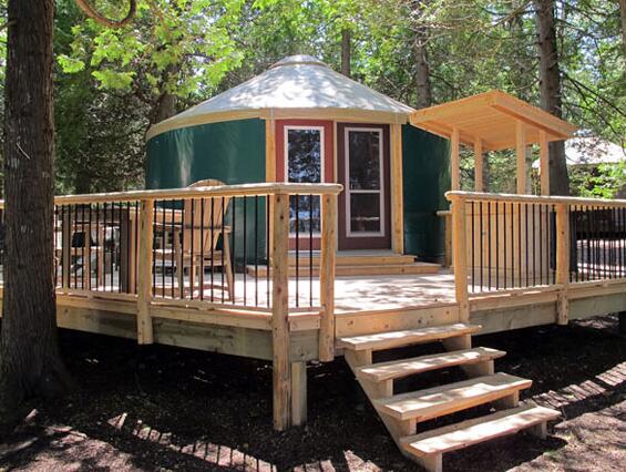Green yurt with white roof and wooden deck