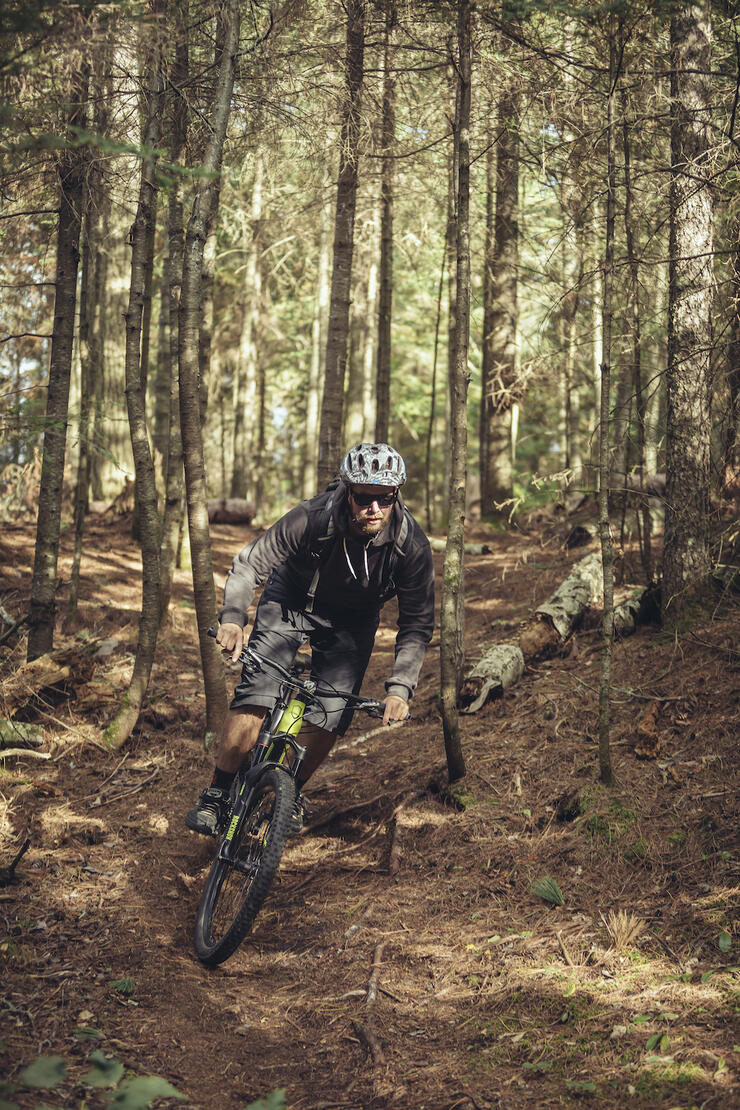 Man rides mountain bike along rough forest track in Trowbridge Forest