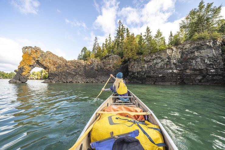 Canoeing toward arch over the water.