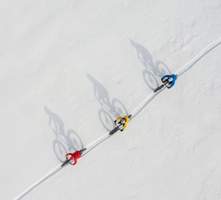Aerial view of three fat bikers riding winter trail