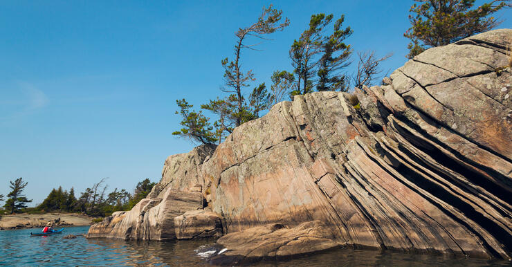 kayaker paddling by large rock island on Georgian Bay