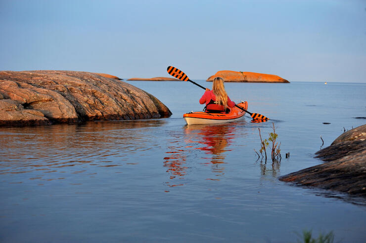 Woman paddling kayak between large rocks on Georgian Bay