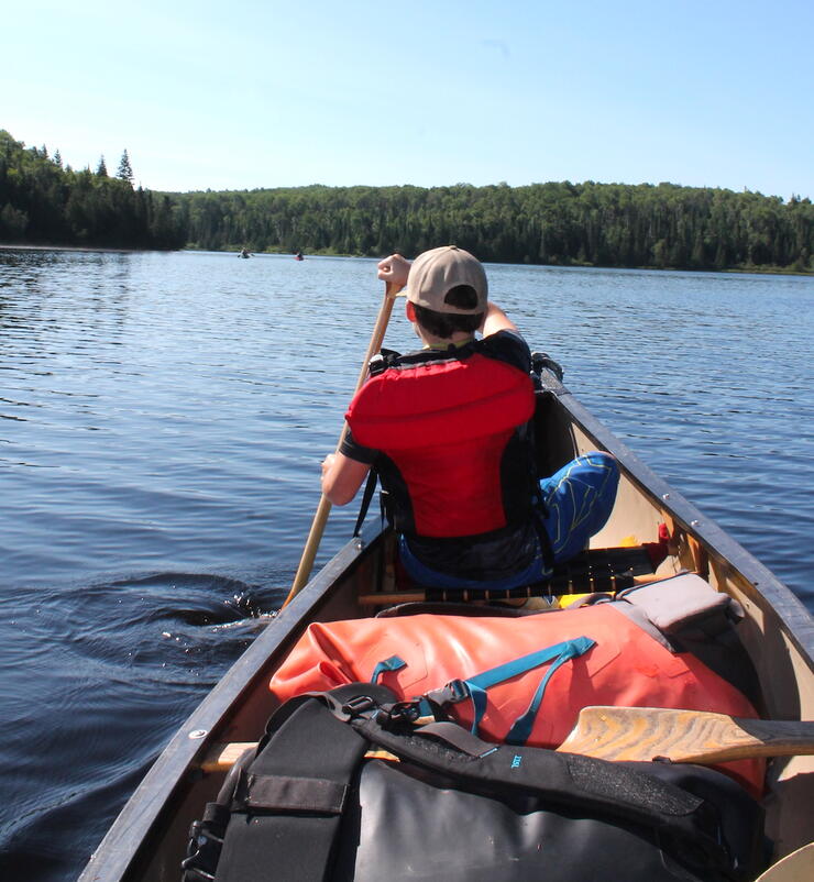 Young boy paddling in bow of canoe