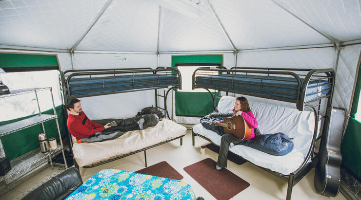 A couple sitting on bunk beds inside a yurt.