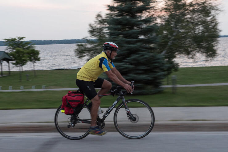 Man cycling on road next to water