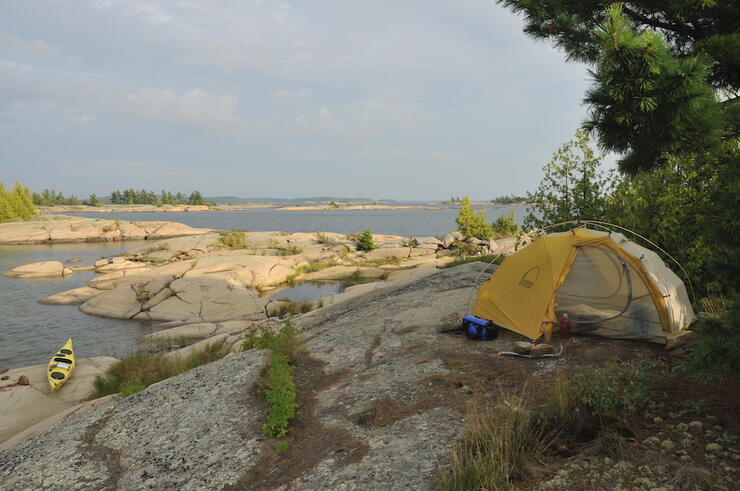 Tent pitched on rocks next to water