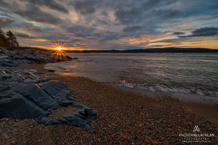 Sunset reflecting over Lake Superior water and rocky shoreline