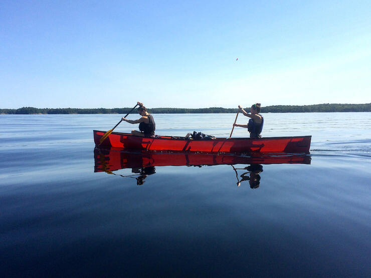 Two people paddling red canoe on a lake