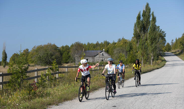Four cyclists riding on a country ride by farmland.