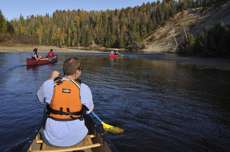 View from back of canoe of two other canoes heading for shore