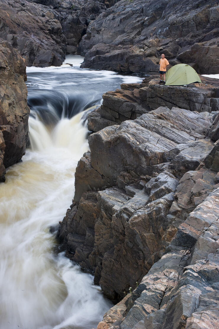 Tent and person at the top of a thundering waterfall