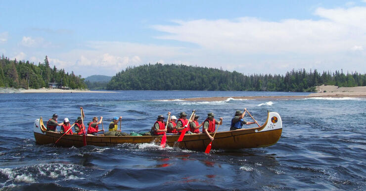 Eleven people paddling a replica voyageur canoe on Lake Superior