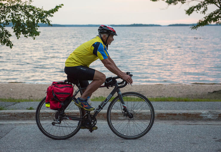 Man riding a bike on a bike path by a lake.