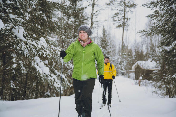 Man and woman on cross country skis going through the forest