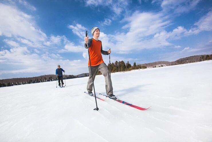 Two people cross country skiing across a frozen, snow-covered lake