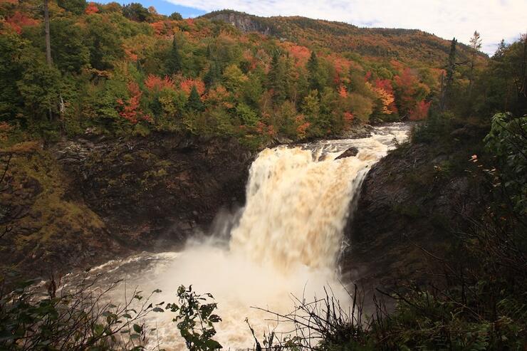 Waterfall surrounded by trees changing colour in autumn