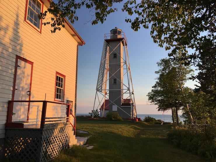 Lighthouse sits beside a building in evening light