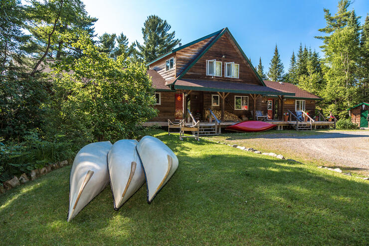 Smoothwater Outfitters and Lodge with three canoes parked on the lawn out front