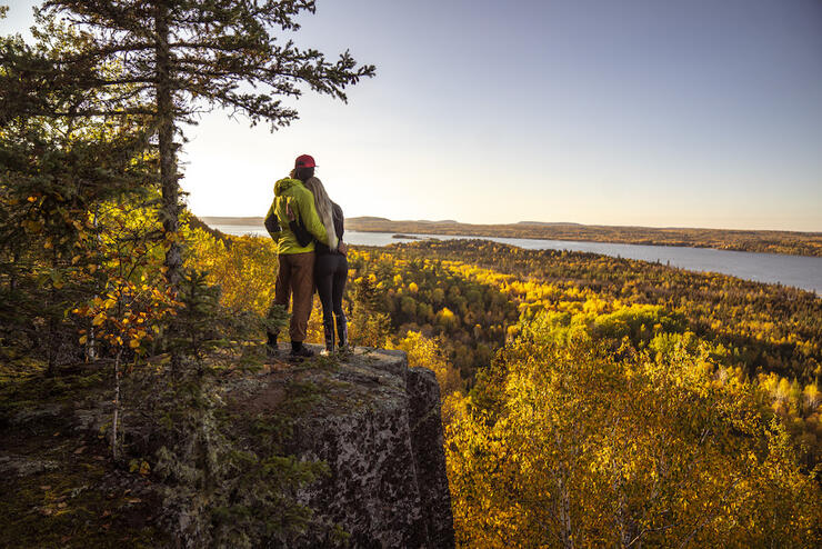 Couple embracing on the edge of a cliff looking at the autumn leaves