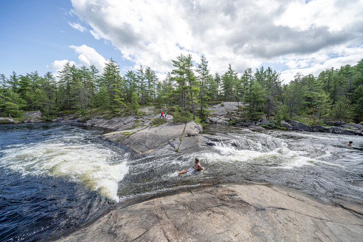 Person sliding down a small sloped waterfall like a water slide