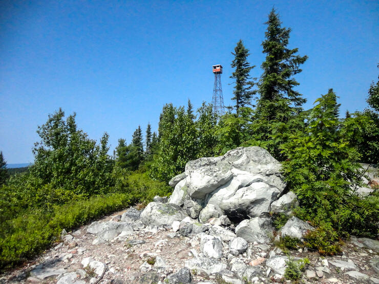 Lookout tower stands over a rocky hill with trees