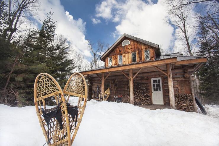 A log cabin with snowshoes placed in the snow